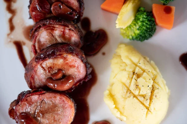 Domuz pastırmasına sarılı domuz filetosu ve patates püresiyle servis edilen tatlı sos.