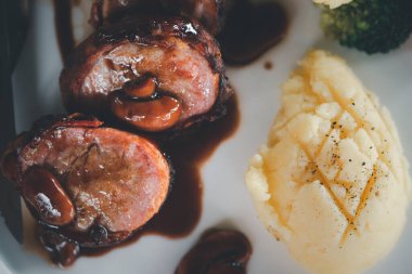 Patates püresiyle servis edilen domuz pastırması ve lezzetli rulo. Üst görünüm