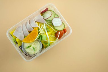 Sarı arka planda plastik kutuda meyve salatası paketlenmiş. Sağlıklı bir yemek.
