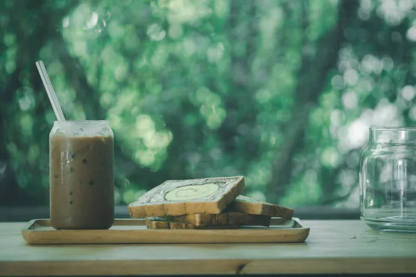 Breakfast set of iced Mocha coffee and slice bread on wood tray