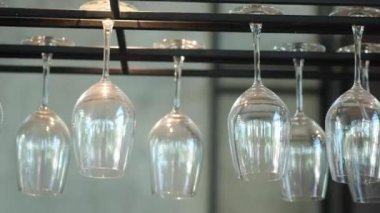 Temiz şarap kadehleri bir bar rafının üstünde baş aşağı asılı duruyor.