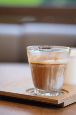 Kirli kahve, buzlu sütten yapılma. Bardaki ahşap kafede bir fincana eklenmiş espresso.