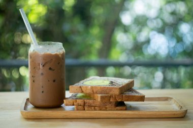 Evde ahşap tepside kaygan ekmekli moka buzlu kahve.