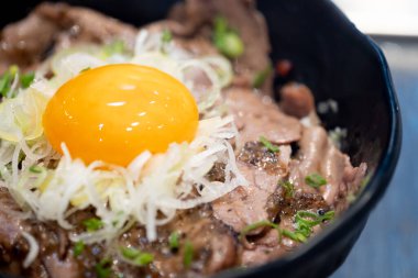 Kızarmış sığır eti ve yumurta sarısını siyah kasede karıştır. Seçili odak.