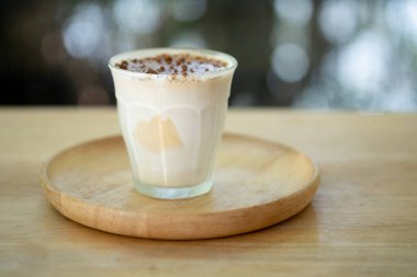 Ahşap masada bir bardak kirli kahve. Sıcak espresso ile kaplanmış soğuk süt.