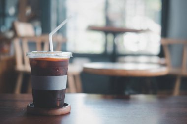 Buzlu sade kahve. Ahşap masada portakal suyu.