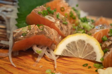 Tahta tabakta dilimlenmiş limonla servis edilen somon balığı yanığı. Japon yemeği tarzı. Seçici odak.