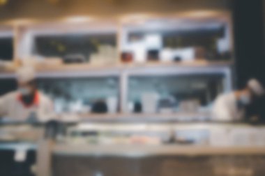 Sushi restoranının bulanık arka planı ve şef suşi yapıyor.