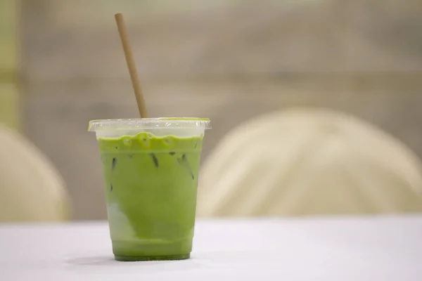 Iced green matcha tea in glass with paper straw