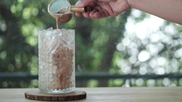 Close Mão Derramando Café Para Vidro Café Gelado Mesa Madeira — Vídeo de Stock