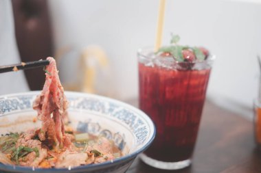 Tayland erişte kasesindeki çubukları kullanarak Wagyu bifteğinden bir dilim aşırmak. Seçici odak