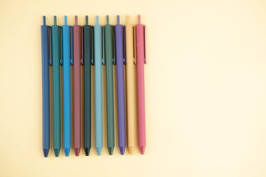 Sarı arka planda çok renkli jel kalemler. Kopya alanı olan ofis ve okul malzemeleri.