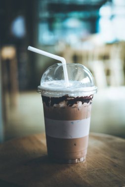 Kahve dükkanının ahşap masasında plastik bardakta buzlu kahve. Tazeleyici içecek.