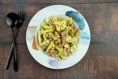 Kızarmış karnabahar ve domuz eti ile istiridye sosu tarifini tabakta karıştır.