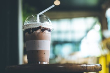 Kahve dükkanının ahşap masasında plastik bardakta buzlu kahve. Tazeleyici içecek.
