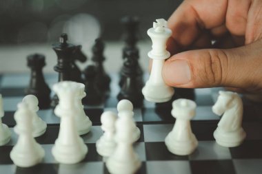 Satranç tahtası oynamak için satranç taşını elle tutan bir adam. Satranç oyunu antrenman stratejisi ve düşünme.