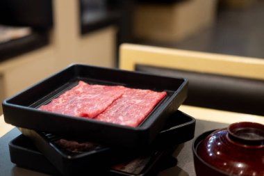 Japon shabu shabu sukiyaki restoranında çiğ et ve çiğ domuz eti ile siyah tepsi.