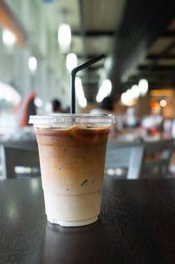 Lokantada ve kafede ahşap masada plastik bardakta buzlu kahve.