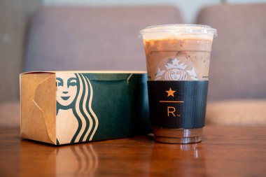 Samut Prakan, Tayland - 7 Şubat 2021 Starbucks buzlu kahve kahvesi ve kek Starbucks Cafe Cafe 'de paket servis masasında. Starbucks soğuk içecek kahve markası ABD kökenlidir.