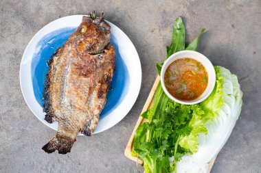 Tuzlu kızarmış Tilapia balığı, Tayland baharatlı sos ve taze sebze, Tayland usulü yemek.