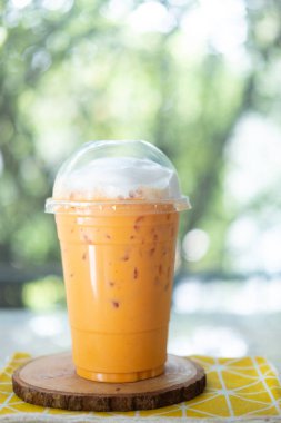 Kremalı sütlü Tayland çayı ahşap masada plastik bardakta