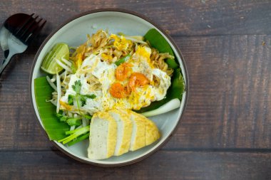 Kızarmış erişte ya da kızarmış Vietnam domuz sosisiyle ahşap masada servis edilen Pad mee korat.