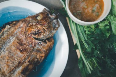 Tuzlu kabuklu ızgara tilapia balığı taze sebzeyle servis edilir ve deniz ürünleri sosu sağlıklı bir Tayland yemeğidir..