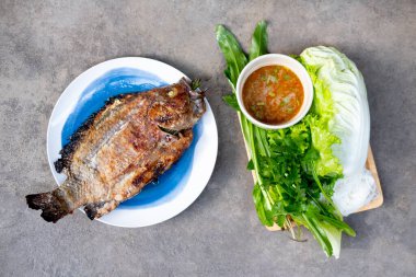 Izgara balık ve baharatlı deniz ürünleri sosu taze sebzeyle yemek sağlıklı bir Tayland yemeğidir.