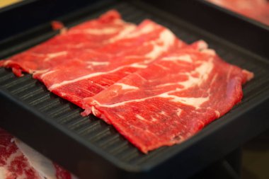 Japon wagyu bifteği siyah tepside sukiyaki için dilimlenmiş.