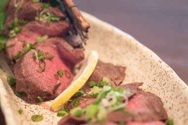 Bir dilim Japon wagyu bifteği üzerine soğan serpilmiş..