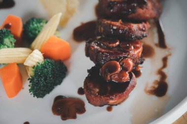 Pastırmalı, soslu biftek, patates kızartması ve kızarmış sebze..