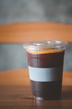 Kahve dükkanındaki ahşap masada dilimlenmiş portakal parçasıyla süslenmiş espresso kahve ile doldurulmuş buzlu portakal suyu.