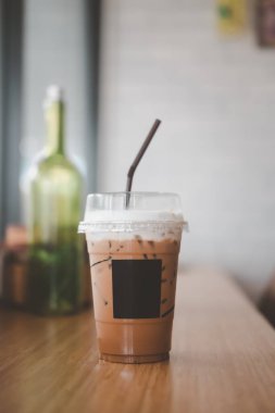 Plastik bardakta buzlu Mocha kahvesi. Kafedeki ahşap barın üstüne.