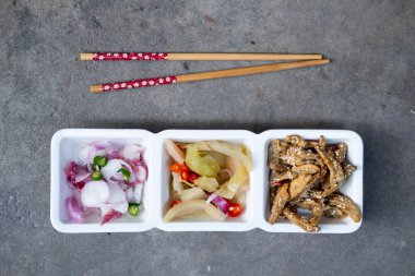 Kızarmış balık, dilimlenmiş kırmızı soğan ve haşlanmış pilavla birlikte yemek için Çin lahana turşusu gibi mezeler.