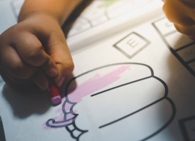 Asyalı çocuk pastel boyalarla kağıt üzerinde resim yapmayı öğreniyor. Seçici odak