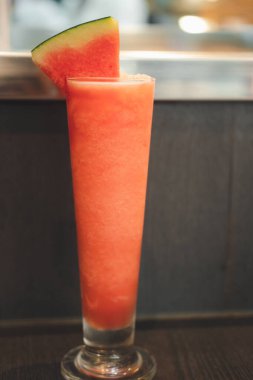 Karpuz parçasıyla süslenmiş uzun bir bardakta kırmızı karpuz smoothie.