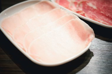 Beyaz tabakta Sukiyaki ve Shabu 'ya servis edilen az pişmiş domuz eti..