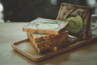 Tahta tepside servis edilen bir dilim mermer çikolata ve rulo pandan.