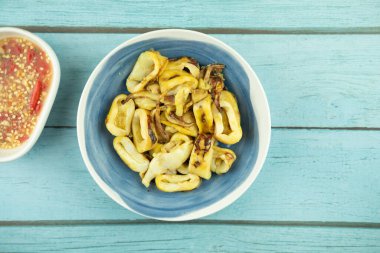 Baharatlı sosla servis edilen ızgara kalamar dolması.