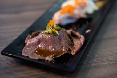 Uçan balık yumurtası ile ızgara Wagyu bifteği ya da üstünde siyah uzun tabakta servis edilen Tobiko süslemesi.