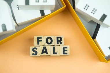 Beyaz minyatür ev modelinin olduğu satılık metin. Promosyon satış evi reklamı konsepti.