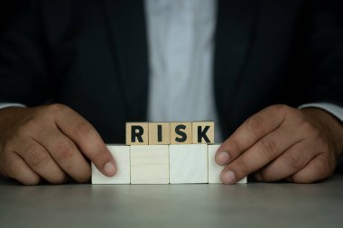 Takım elbiseli bir iş adamı risk içeren tahta küpleri elinde tutar. Risk yönetimi konsepti. Risk değerlendirmesi, iş görüşmelerini kabul etme kararı belirsizlik, öngörülemez durum kavramı