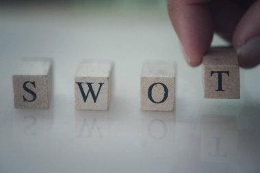Hand putting wooden cube with swot analysis.  SWOT analysis concept. Strengths, weaknesses, threats and opportunities of company