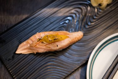 Siyah tabakta servis edilen ızgara somon ya da yanmış suşi..