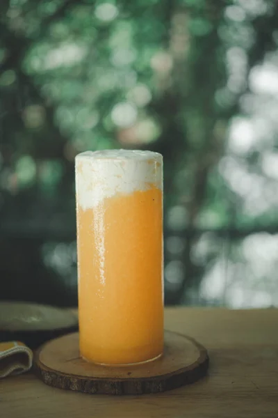 木のテーブルの上の場所にミルククリームと茎のないガラスの健康的なスムージーオレンジジュース — ストック写真