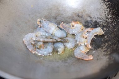 Tayland yemeği için tavaya taze karides koyuyorum.