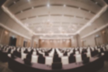 Toplantı bittikten sonra boş seminer odasının bulanık arkaplanı ve seminer odası arka planında seyirciler dışarı çıkıyor. Balık gözü mercekli bir fotoğraf çek.