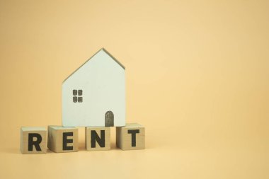 Ahşap bloklar, üzerinde sarı arka planlı ahşap evler olan RENT harfleri. Ev kirası kavramı