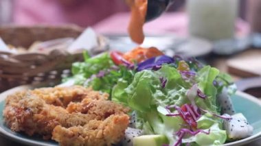 Sebze ve kızarmış tavuğa salata sosu dök..