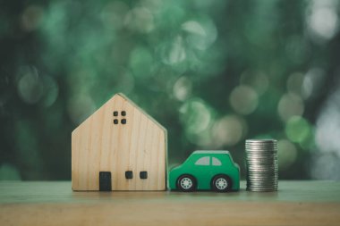 Ahşap ev ve araba, iş fikri ve kâr kavramında ahşap zeminde madeni paranın yanına yerleştirildi.